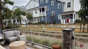 A residential outdoor area with a patio, artificial grass, a stone pillar, and a fence.