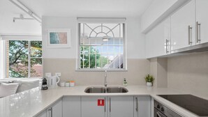 Een moderne keuken met een groot raam, roestvrijstalen apparatuur en een minimalistisch ontwerp.
