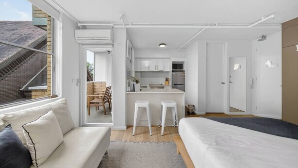 Een modern appartement met een zithoek, kitchenette en balkon.