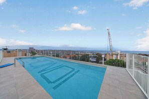 Ein Pool auf dem Dach mit Blick auf Stadt und Meer.