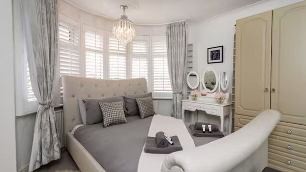 A bedroom with a large bed, a vanity with mirrors, and a wardrobe. - Beautiful Escape | Wi-Fi | Garden & Free Parking - Pass the Keys (Nottingham)