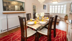 A dining area with a table set for six, chairs, a chandelier, and a window with blinds. - Beautiful Escape | Wi-Fi | Garden & Free Parking - Pass the Keys (Nottingham)