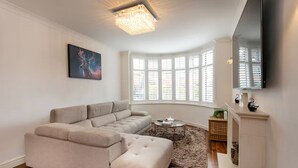 A living room with a sectional sofa, a coffee table, a fireplace, and a large window with blinds. - Beautiful Escape | Wi-Fi | Garden & Free Parking - Pass the Keys (Nottingham)