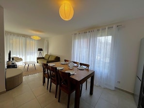Un coin repas avec une table dressée pour quatre personnes, un canapé, un téléviseur et une lampe.