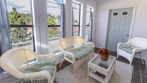 A balcony with wicker furniture, a glass coffee table, and a door. - The Golden Getaway in Lead (Lead)