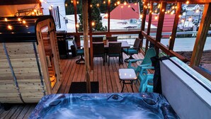 A hot tub with a wooden deck, outdoor seating, and string lights. - The Golden Getaway in Lead (Lead)