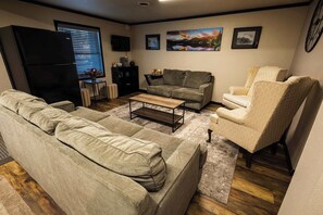 Un salon comprenant un canapé, un fauteuil, une table basse et un téléviseur.