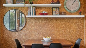Un comedor con una mesa de madera, sillas, un espejo redondo y un reloj en la pared.