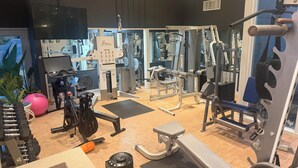 Un gimnasio con equipo de ejercicio variado, que incluye una cinta de correr, máquinas de pesas y una bicicleta estática.