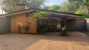 Una casa moderna de un solo piso con entrada de grava, un porche cubierto y una chimenea de ladrillo.
