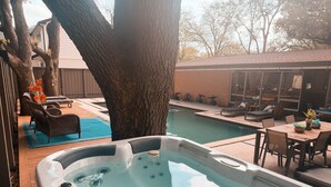 Tuberculo de hidromasaje con piscina, mobiliario exterior y un gran árbol.