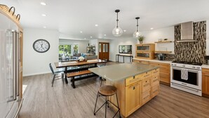 Una cocina moderna con una isla central, armarios de madera, electrodomésticos de acero inoxidable e iluminación colgante.