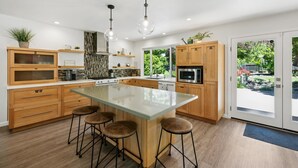 Una cocina moderna con una isla grande, armarios de madera e iluminación colgante.