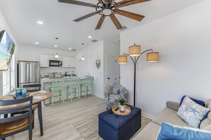 Una cocina moderna con armarios blancos, un refrigerador de acero inoxidable y una zona de comedor con una mesa redonda y sillas.