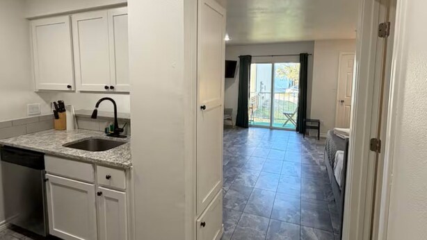 A kitchen with white cabinets, a sink, and a dishwasher. - 1-bedroom studio with AC in vibrant TX (Austin)