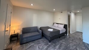 A bedroom with a bed, a sofa, a nightstand, and a lamp. - 1-bedroom studio with AC in vibrant TX (Austin)