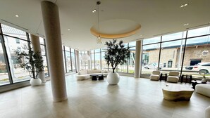 Un hall d’entrée spacieux, doté de grandes fenêtres, de mobilier moderne et d’une colonne centrale.
