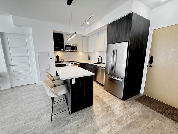 Una cocina moderna con una isla central, electrodomésticos de acero inoxidable y un diseño minimalista.