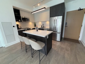 A modern kitchen with a central island, stainless steel appliances, and a built-in microwave.