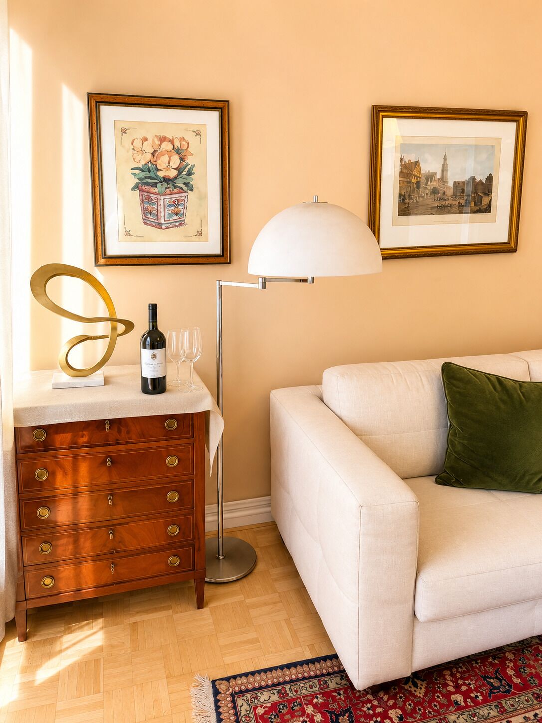 A living room with a sofa, a wooden dresser, a floor lamp, and two framed pictures on the wall.
