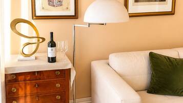 A living room with a sofa, a wooden dresser, a floor lamp, and two framed pictures on the wall.
