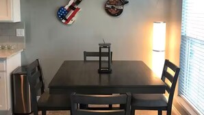 Un comedor con una mesa, sillas y dos guitarras colgadas en la pared.