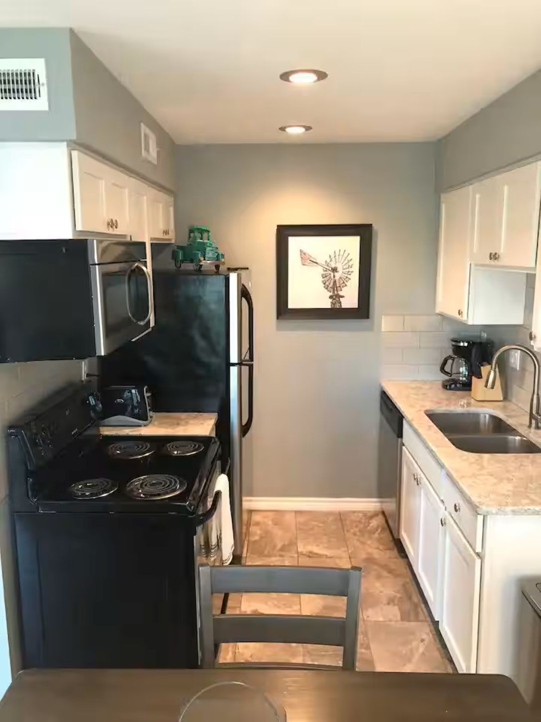 Una cocina compacta con estufa, microondas, refrigerador y pileta.