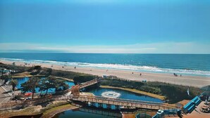 Ein Küstenresort mit Promenade, Strand und großem Poolbereich.