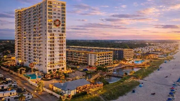 Ein Hochhotel mit Pool, Strand und Blick auf den Sonnenuntergang.