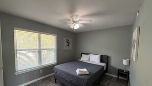 A bedroom with a bed, a ceiling fan, a window with blinds, and a bedside table. - Perfect studio with AC in welcoming TX-3 (Austin)