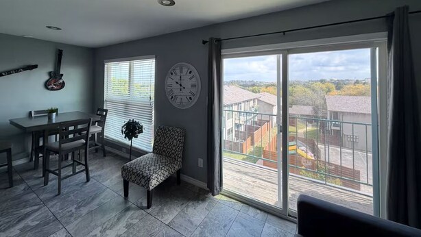 A spacious living room with a dining area, a large window with a view of the neighborhood, and a clock on the wall. - Perfect studio with AC in welcoming TX-3 (Austin)