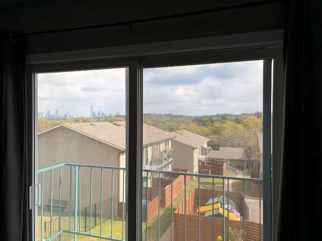 A view through a window of a residential area with houses and a distant city skyline.