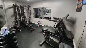 Une salle de sport équipée de matériel de musculation, de bancs et d’un miroir.