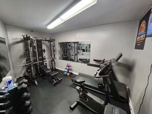 A gym with weightlifting equipment, benches, and a mirror. - The Ocean Sky (Myrtle Beach)