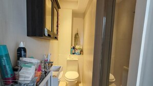 Ein kleines Badezimmer mit Toilette, einem Ablagefach für Pflegeprodukte und einem kleinen Spiegel.