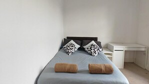 Ein Schlafzimmer mit einem Bett, zwei Kissen, einem Schreibtisch und einem Stuhl.