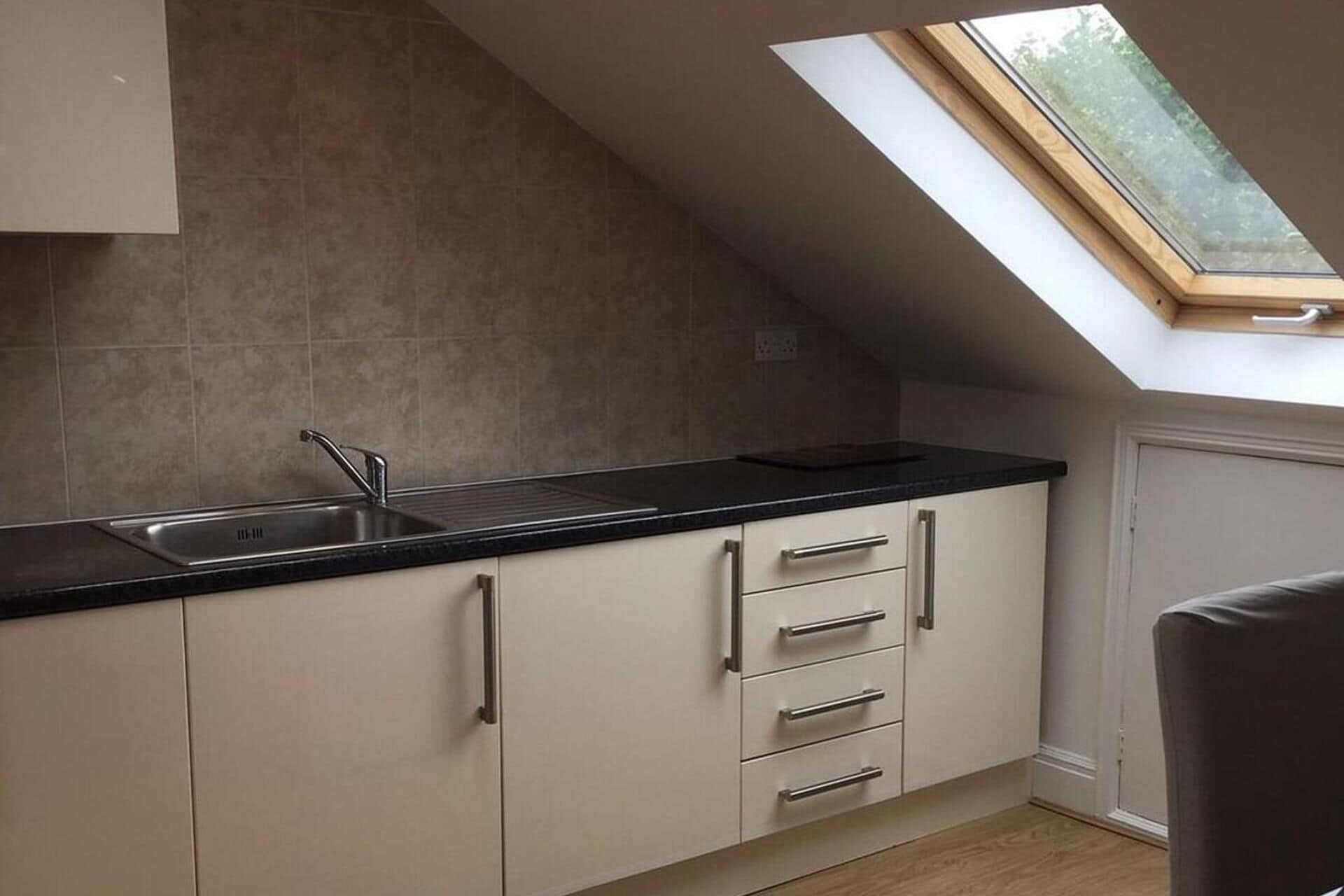 A kitchen with a skylight, a sink, and cabinets.