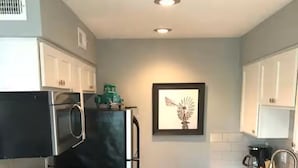 A compact kitchen with a stove, microwave, refrigerator, and a sink. - 1-bedroom studio in TX with AC for your stay (Austin)