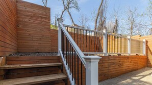 A wooden staircase with a white balustrade leading to a deck area. - Spacious Home with Porch Sleeps 6 Near Pitt & UPMC (Pittsburgh)