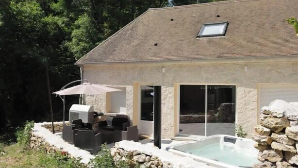 A house with a swimming pool, outdoor seating, and a stone wall.