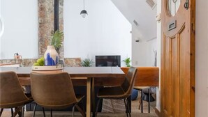 A dining area with a wooden table, brown chairs, a vase with fruits, and a television. - Quirky & Fun 4 Bedroom Home in Travis Heights (Austin)