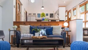 A modern living room with a sofa, coffee table, and blue poufs. - Quirky & Fun 4 Bedroom Home in Travis Heights (Austin)