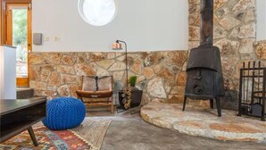 A stone wall, a round window, a black stove, a chair, and a blue bean bag. - Quirky & Fun 4 Bedroom Home in Travis Heights (Austin)
