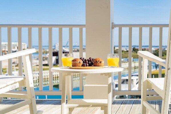 Un balcon avec une table préparée pour le petit-déjeuner, comprenant un muffin, des raisins et des verres de jus d’orange.