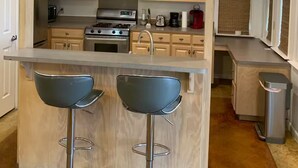 Eine moderne Küche mit Holzschränken, Edelstahlgeräten und einer Bar mit zwei Hockern.