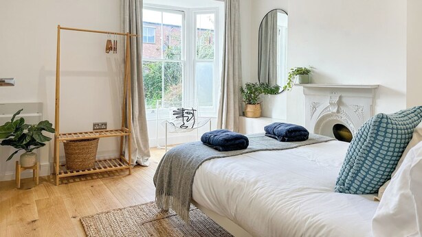 Une chambre à coucher avec un lit, une étagère en bois, un miroir, une cheminée et une vue par la fenêtre.