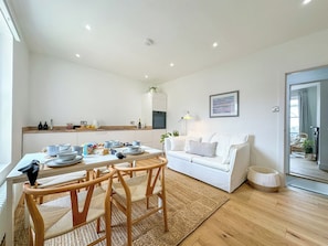 A modern living room with a white sofa, wooden dining table, and chairs. - New | Luxury City Centre Oasis | Private Parking (Canterbury)