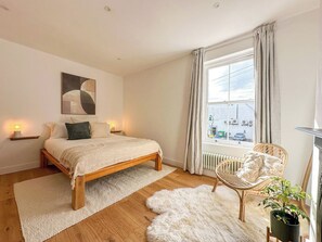 Une chambre à coucher avec un lit, une chaise, une fenêtre et un radiateur.
