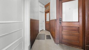 Ein Korridor mit einer Holztür, einer weißen Wand und einer Deckenleuchte.