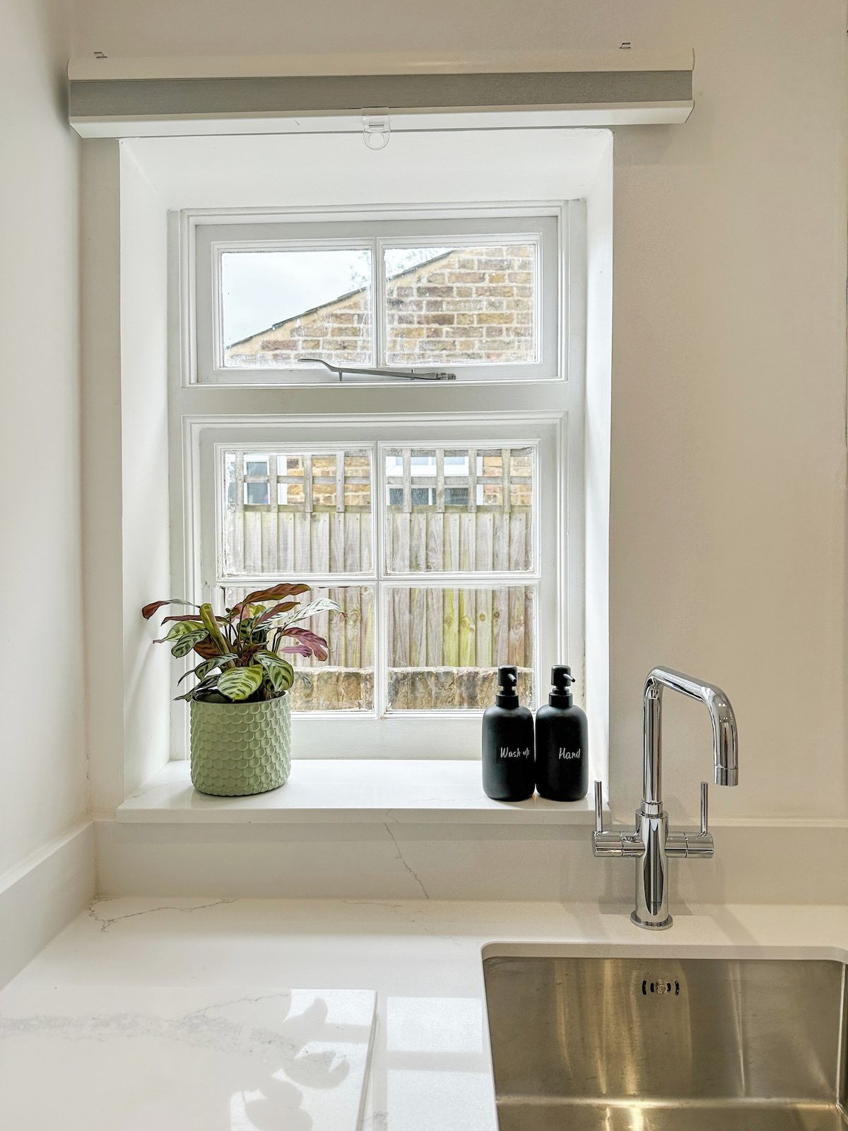 A kitchen with a window, a sink, and two bottles on the windowsill.